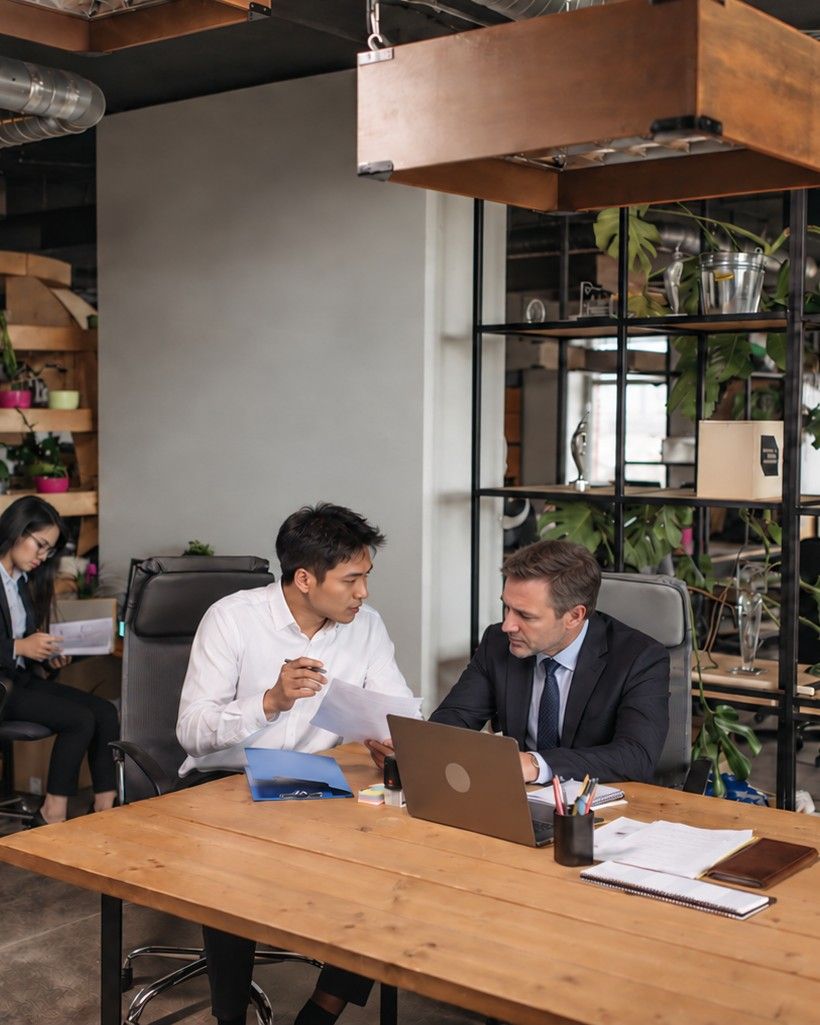 A team lead going through papers with a client at a laptop